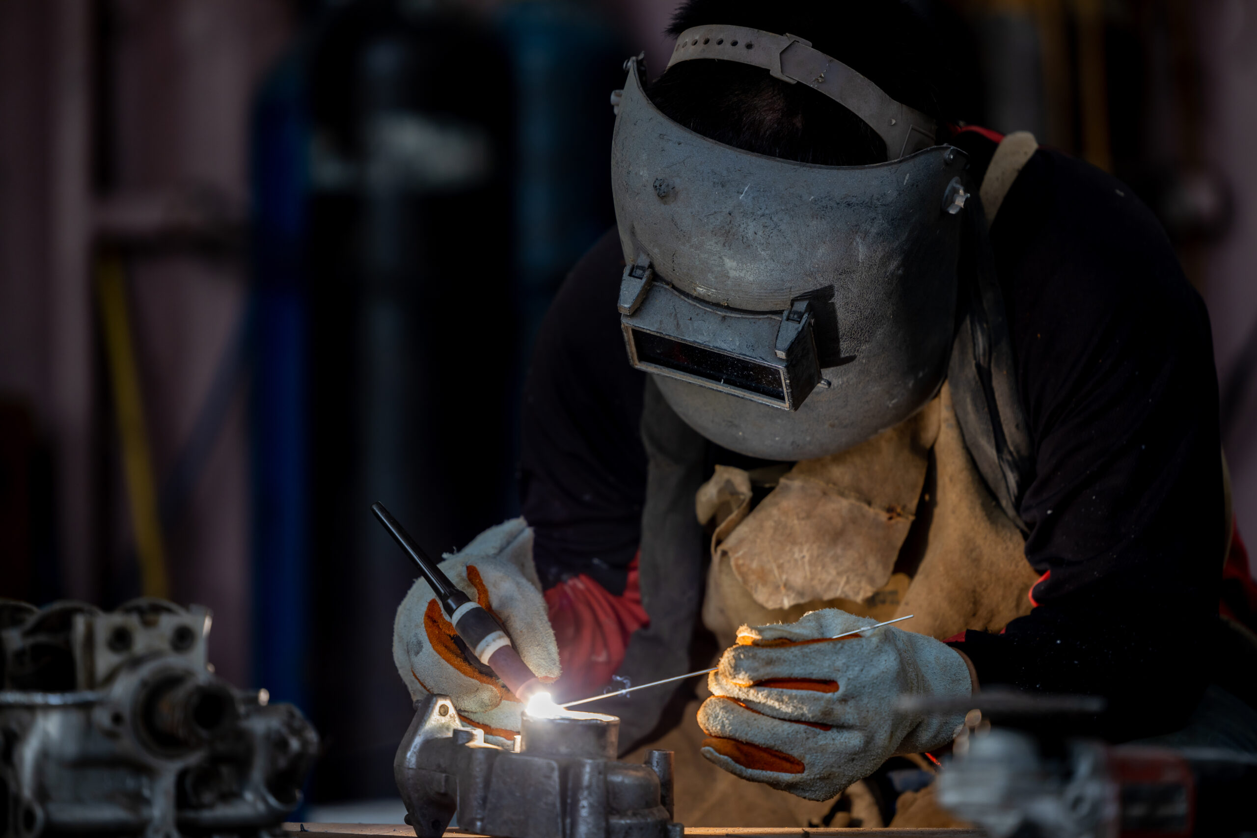 La fusione dell'arte e della precisione: un esperto saldatore con maschera TIG lavora con maestria, plasmando il metallo con la perfezione della saldatura TIG.